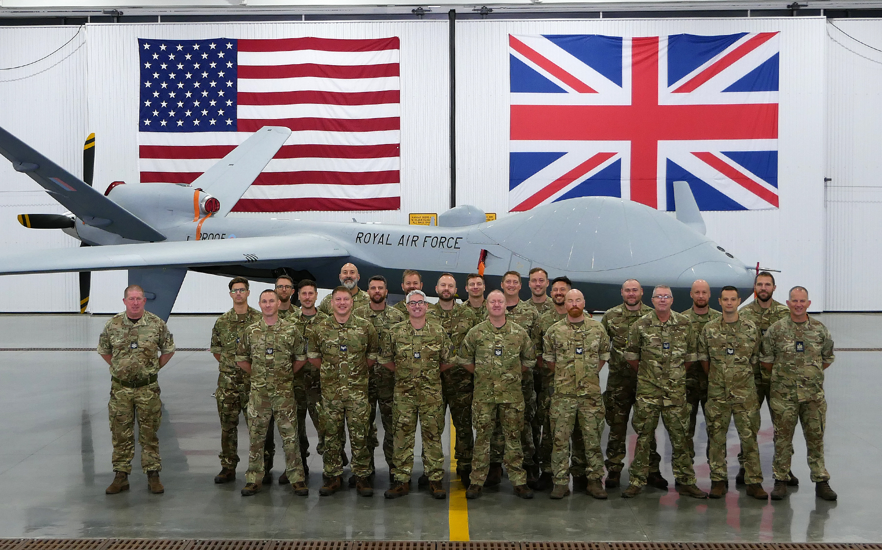 Image shows RAF squadron photo with the Protector aircraft and flags of the UK and USA.
